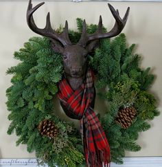 a deer head mounted to the side of a wall next to a wreath with pine cones