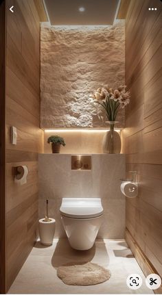 a white toilet sitting inside of a bathroom next to a wooden wall