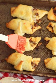 several pastries on a baking sheet with a spatula in the foreground and red checkered table cloth