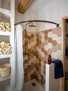 a bathroom with hexagonal tiles on the shower wall and shelves filled with towels