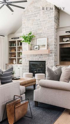 grey sofa, gray sofa, grey couch, gray couch, magazine holder, stone fireplace, ottoman, wood mantle, faux greenery, fake plants, large fan, built-in shelving, shelf accessories, art inspo, family room, living room, great room, pillows, poofs, Living Room Fireplace Shelving, Tv Next To Fireplace Layout, Design Camino, Cabin Renovation, Cabin Fireplace, Transitional Farmhouse, Capstone Project, Modern Farmhouse Living, House Family