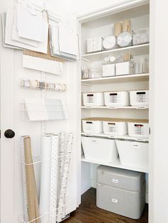 an organized pantry with white bins and baskets