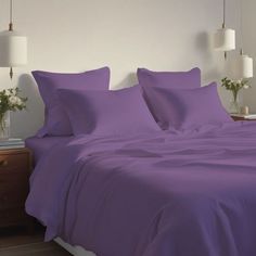 a bed with purple sheets and pillows in a room