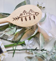 a wooden spoon with an arrow on it next to some white flowers and greenery