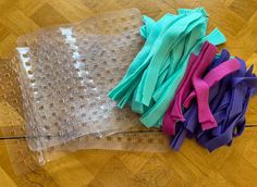 several pieces of plastic sitting on top of a wooden floor next to a bag filled with fabric