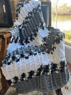 a crocheted blanket sitting on top of a wooden chair next to a fire place