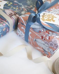 two wrapped presents with blue ribbon on white tablecloth and decorative wrapping around the edges