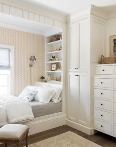 a white bed sitting in a bedroom next to a dresser under a window on top of a hard wood floor