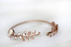 This stunning and unique bracelet is based on a strong and adjustable base that is decorated on each side with a beautiful long and detailed twig leaves, along with some pearls and crystals. This piece is so dainty and feminine. It will be a stunning edition to a special even just as much as a delicate piece to wear on an everyday basis. Circumference is around 15cm / 6inch. This size could be slightly adjusted to become bigger or smaller.* Comes wrapped in a pretty gift packaging* Comes in 14k Unique Metal Bracelets For Weddings, Unique Wedding Metal Bracelets, Delicate Metal Bracelets For Wedding, Bohemian Crystal Bangle Bracelet For Wedding, Gold Bohemian Crystal Bracelet For Wedding, Dainty Metal Bracelet For Wedding, Delicate Metal Wedding Bracelets, Bohemian Gold Crystal Bracelet For Wedding, Leaves Bracelet