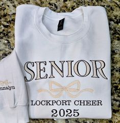 SENIOR 2025 Sweatshirt with bow, Trendy high school senior Sweatshirt, Embroidered Sweatshirt, Cute Sweatshirt, For Her. Great Senior night team shirts.  Message for bulk orders.  be sure you are ordering the option you want. There are T-shirts, Crewnecks or Hoodies. Bow and name on the cuff is an optional add on for sweatshirts or hoodies ONLY. **  Choose the size with +cuff to add the sleeve design to your order.  We offer a variety of custom made embroidered shirts.  See photos above for sizing.  The primary color is the shirt color.  Visit the rest of our shop at KikiLeeOriginals.etsy.com  Thank you for visiting! Unisex sizes. Available in crewneck or hoodie or t-shirts. 99% of the shirts are Gildan brand heavy weight cotton/polyester.  Occasionally an equivalent brand will be used. Senior Sweatshirts, Sweatshirts Cute, Team Sweatshirts, Embroidered Shirts, Class Of 2025, Sweatshirt Trendy, Senior Night, Cute Sweatshirts, Embroidered Sweatshirt