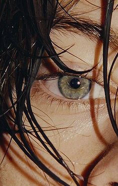 a close up of a person's eye with long hair on top of it