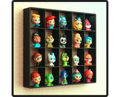 there are many small toy figures in the shelf on the wall behind it is a black frame