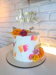 a birthday cake decorated with flowers and the words happy birthday on it's side