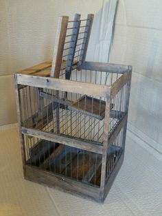 an old birdcage is sitting on the floor next to a white sheeted wall