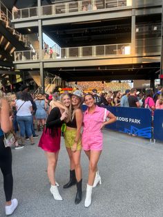 three women standing next to each other in front of a crowd at a sporting event