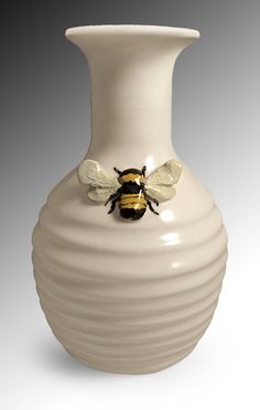 a white vase with a yellow and black bee on it