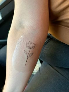 a woman's arm with a small flower tattoo on the left side of her arm