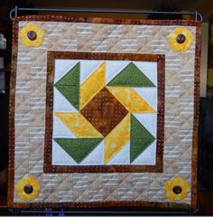 a quilted wall hanging with yellow and green flowers on it's center piece