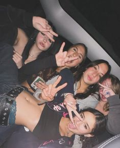 a group of young women posing for a photo in the back of a car with their fingers up