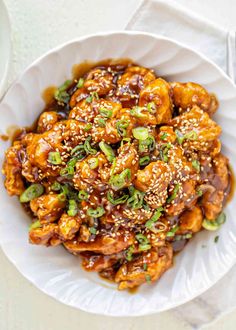 a white plate topped with chicken covered in sesame seeds