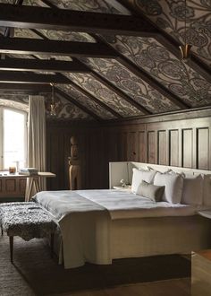 a large bed sitting in a bedroom next to a wooden wall and ceiling covered in wood paneling