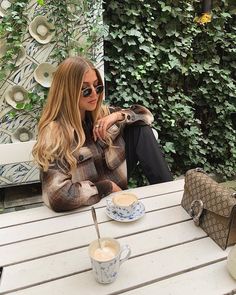 a woman sitting at a table with a cup of coffee