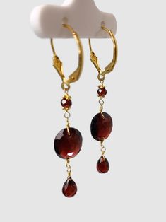 Garnet 3 station drop earring. each earring features a 10x12mm oval faceted checkerboard bead in the middle of a 3mm faceted round bead and 4x7mm briolette pear drop. Earrings are 14k yellow gold and 2.1" long. Metal - 14k Yellow Gold Gemstones - Garnet Length - 2.1" Drop Earring, In The Middle, Round Beads, The Middle, Garnet, Pear, Yellow Gold, Drop Earrings, Gemstones