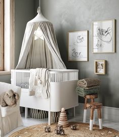 a baby's room with a white crib in the corner and pictures on the wall