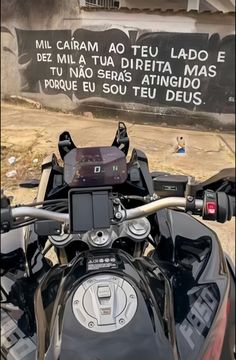 a motorcycle parked in front of a building with graffiti on the side of it's wall