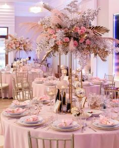 the table is set with pink flowers and gold plates, silverware and wine glasses