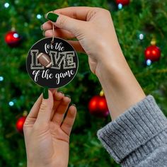 someone holding up a christmas ornament with mistletde mode on it in front of a christmas tree