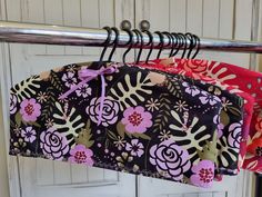 two purses hanging from a metal rack with flowers on them and one has a pink flower