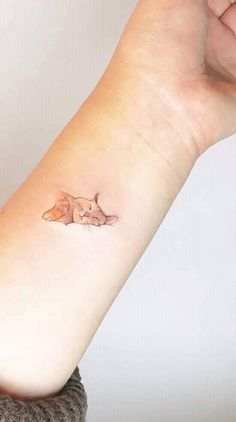 a woman's arm with a small fox tattoo on the left side of her arm