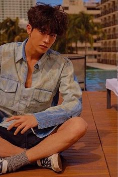 a young man sitting on the ground next to a pool