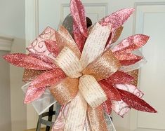 a large pink and gold bow on top of a chair