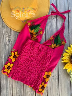 This Beautiful Sunflower Embroidered Halter Top is the perfect Top for Everyday use or a special event. It is comfortable, with elastic on the back and has a tie around the neck for an adjustable fit. This blouse comes in one size which fits sizes Small and Medium. Fitted Embroidered Top For Summer Beach, Fitted Floral Embroidered Top For Festival, Fitted Summer Embroidered Top With Geometric Design, Fitted Summer Top With Geometric Embroidery, Fitted Summer Embroidered Top With Geometric Embroidery, Fitted Pink Embroidered Top With Floral Details, Fitted Pink Top With Floral Embroidery, Fitted Embroidered Top With Geometric Design For Summer, Summer Folk Style Embroidered Top