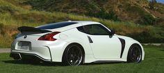 a white sports car parked on the side of a road next to a grassy hill