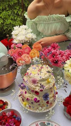 a woman sitting in front of a table filled with cakes and flowers