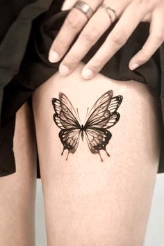 a woman's thigh with a black and white butterfly tattoo on the side of her leg