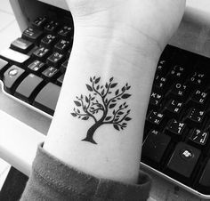 black and white photo of a tree tattoo on the left wrist by a computer keyboard