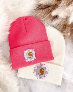 two beanies sitting next to each other on top of a white furnishing