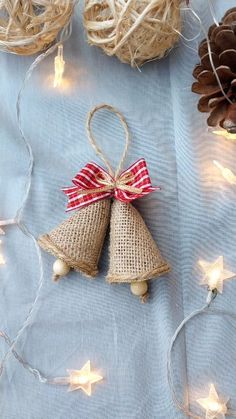 two burlap bell ornaments with red ribbon tied around them on a blue background