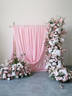 pink and white flowers are arranged in front of a drapeed backdrop for a wedding ceremony