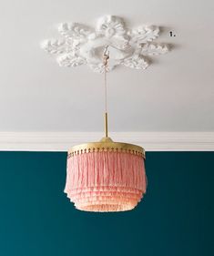 a pink chandelier hanging from the ceiling in a living room with blue walls