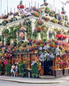 two people standing in front of a building with flowers on it