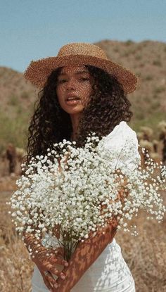 a woman in a straw hat is holding some baby's breath flowers and looking at the camera