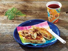 pancakes on a blue plate with a cup of tea and napkins next to it