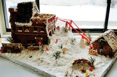 a gingerbread house made to look like it has been built into the snow and is in front of a window