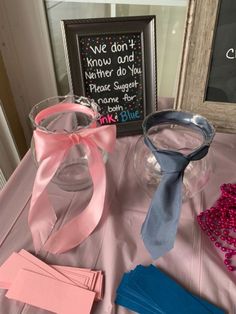 a table topped with pink and blue items next to a framed chalkboard sign that says we don't know and another do you