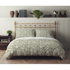 a bed with green and white bedspread next to a book shelf filled with books